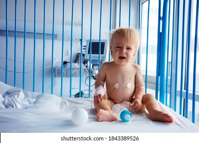 Little One Year Old Toddler Sit In Hospital Bed And Cry With Catheter In His Hand