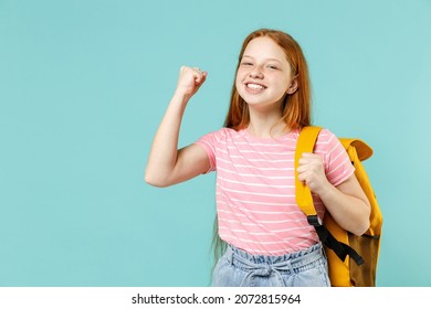 Little overjoyed pupil redhead kid girl 12-13 year old in pink t-shirt yellow school bag backpack do winner gesture clench fist isolated on pastel blue background Children lifestyle childhood concept - Shutterstock ID 2072815964