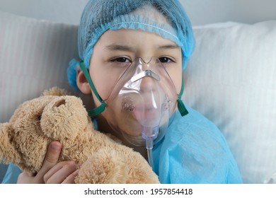 Little Patient In Shirt, Child, Boy Lies With Teddy Bear, Facial Oxygen Mask, Concept Of Medical Care, Anesthesiology And Intensive Care, Oxygen Therapy, Treatment Of Coronavirus, COVID-19