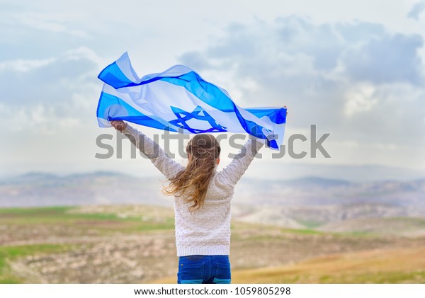 青い空の背景にイスラエルの国旗と共に立ち楽しむ愛国者のユダヤ人の少女 記念日 ヨム ハジカロン 愛国的な祝日の独立記念日 イスラエル の写真素材 今すぐ編集
