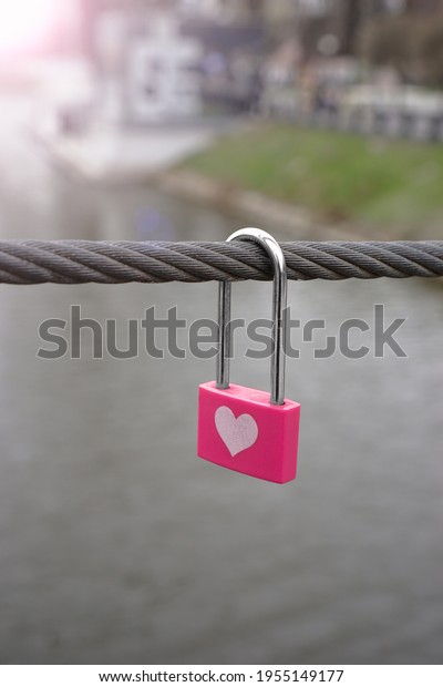 Little\
pink lock on wire rope. Love lock on the\
bridge.