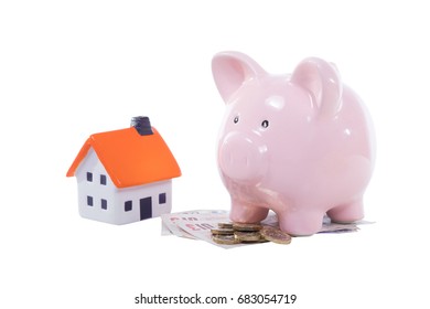 Little Pink Piggy Bank With A Pile Of UK Money And A Model House Isolated On White In A Concept Of Saving, Deposit, Mortgage And Purchase Of Property