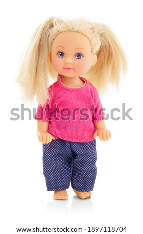 little plastic doll, baby girl. Little blonde doll with blue eyes on white bg. Isolated on white background with shadow reflection. With red shirt and checkered pants.