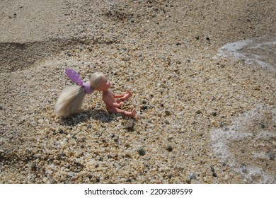 Little Plastic Doll On The Sand Beach	