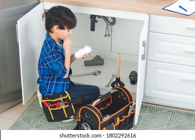 Little Plumber Repairing Sink In Kitchen