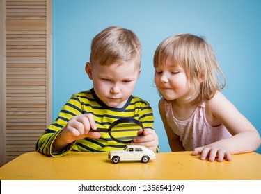 Little Preschool Boy And Girl Observing Toy Car With Magnifying Glass. Child Explores World At Home Or Daycare. Educational Toys For Preschool And Kindergarten Child. 