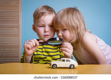 Little Preschool Boy And Girl Observing Toy Car With Magnifying Glass. Child Explores World At Home Or Daycare. Educational Toys For Preschool And Kindergarten Child. 