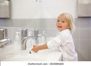 Little preschool child, blond boy, washing hands in bathroom in kindergarden, hygiene habits