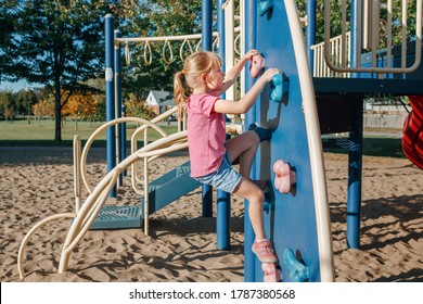 Little Preschool Girl Climbing Rock Wall At Playground Outside On Summer Day. Happy Childhood Lifestyle Concept. Seasonal Outdoor Activity For Kids. Strong Girl Female Power.