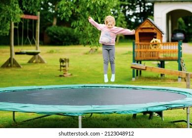 Little preschool girl jumping on trampoline. Happy funny toddler child having fun with outdoor activity in summer. Sports and exercises for children. - Shutterstock ID 2123048912