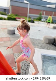 Little Preschool Girl Splashing In An Outdoor Swimming Pool On Warm Summer Day. Happy Healthy Toddler Child Enjoying Sunny Weather In City Public Pool. Kids Activity Outdoors With Water.