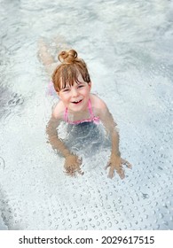 Little Preschool Girl Splashing In An Outdoor Swimming Pool On Warm Summer Day. Happy Healthy Toddler Child Enjoying Sunny Weather In City Public Pool. Kids Activity Outdoors With Water.