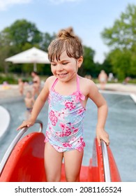 Little Preschool Girl Splashing In An Outdoor Swimming Pool On Warm Summer Day. Happy Healthy Toddler Child Enjoying Sunny Weather In City Public Pool. Kids Activity Outdoors With Water.