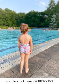 Little Preschool Girl Splashing In An Outdoor Swimming Pool On Warm Summer Day. Happy Healthy Toddler Child Enjoying Sunny Weather In City Public Pool. Kids Activity Outdoors With Water.