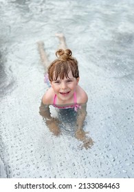 Little Preschool Girl Splashing In An Outdoor Swimming Pool On Warm Summer Day. Happy Healthy Toddler Child Enjoying Sunny Weather In City Public Pool. Kids Activity Outdoors With Water.