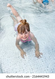 Little Preschool Girl Splashing In An Outdoor Swimming Pool On Warm Summer Day. Happy Healthy Toddler Child Enjoying Sunny Weather In City Public Pool. Kids Activity Outdoors With Water.