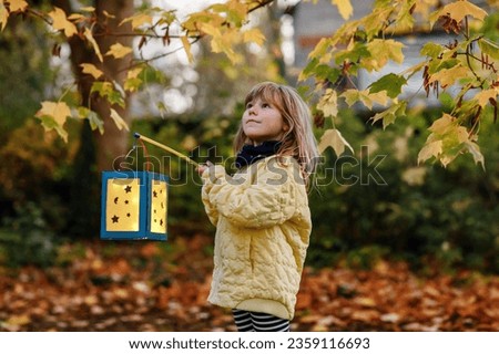 Little preschool kid girl holding selfmade traditional lanterns with candle for St. Martin procession. child happy about children and family parade in kindergarten. German tradition Martinsumzug