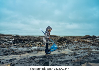 A little preschooler is standing by the sea with a fishing net - Powered by Shutterstock