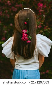 little pretty armenian girl toddler walk in an apple blossoming pink garden, portrait in a spring park among flowering blooming trees from behind, flowers braided in hair
