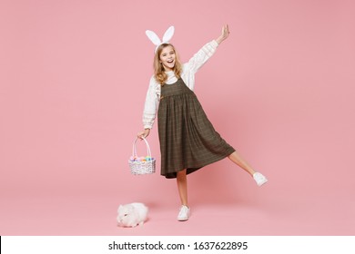 Little Pretty Blonde Kid Girl 11-12 Years Old In Spring Dress Hold Fluffy White Bunny Rabbit Isolated On Pastel Pink Background Children Studio Portrait. Childhood Lifestyle Happy Easter Concept