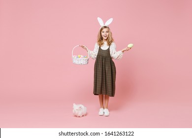 Little Pretty Blonde Kid Girl 11-12 Years Old In Spring Dress Hold Fluffy White Bunny Rabbit Isolated On Pastel Pink Background Children Studio Portrait. Childhood Lifestyle Happy Easter Concept