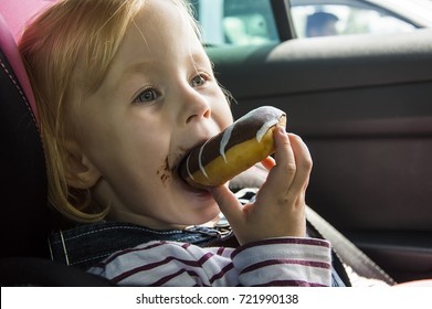 Little Pretty Girl Eating Chocolate Donuts In Car Salon