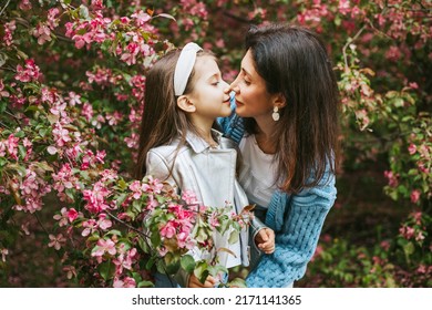 little pretty girl toddler armenian daughter and mother beautiful middle aged woman walk in an apple blossoming pink garden, family portrait in a spring park among flowering blooming trees