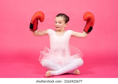 Little Proud Classical Dancer Girl Showing Biceps And Wearing Boxing Gloves With Funny Face. Female Stereotypes Concept.