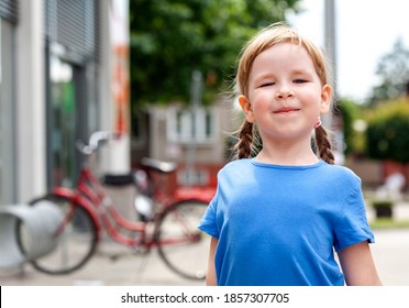 Little proud girl, child standing looking at the camera with chin up, holding head up high, smug face, back straight. Sassy proud pose and expression young kid portrait, closeup, outdoors lifestyle