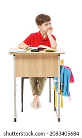 Little Pupil Sitting At School Desk Against White Background