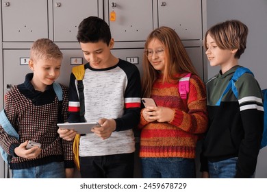 Little pupils using gadgets near locker at school - Powered by Shutterstock