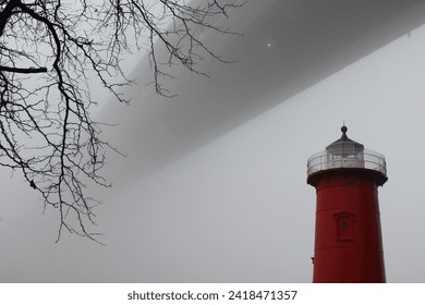 Little Red Lighthouse next to a bare branch under the George Washington Bridge surrounded by thick fog on a winter day in Fort Washington Park, Washington Heights, New York City - Powered by Shutterstock