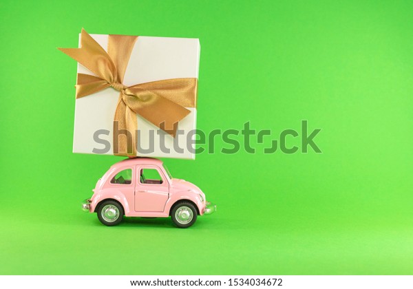 Little retro toy\
model car with present gift box on light green background.\
Christmas, birthday, valentines day, delivery concept. Vilnius,\
Lithuania, September 09,\
2019
