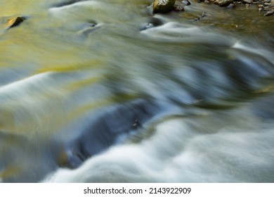 Little River Rapids Captured With Motion Blur And Illuminated By Reflected Color From Sunlit Spring Foliage And Blue Sky Overhead, Great Smoky Mountains National Park, Tennessee, USA