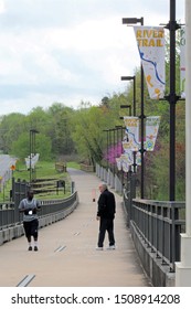 Little Rock AR/USA: March 29, 2018 – Two men stop to chat on Big Dam Bridge incline over Arkansas River. Colorful banners say River Trail and Pulaski County. The bridge is for walkers and bikers only 