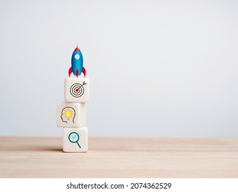 Little Rocket On Top Of White Cube Blocks Stacks With Business Strategy Icons On A Wooden Table On White Background With Copy Space. Small Business And Startup Process For Leadership Concept.