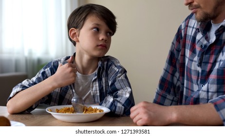 Little Sad Boy Mixing Cornflakes With Spoon, Looking At Father, Poor Appetite