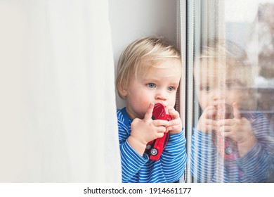 Little Sad Boy Sitting At Home On Window In Rainy Day. Stay Home Coronavirus Concept.