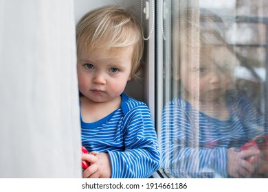 Little Sad Boy Sitting At Home On Window In Rainy Day. Stay Home Coronavirus Concept.