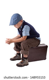 Little Sad Boy Is Sitting On A Case Isolated On White