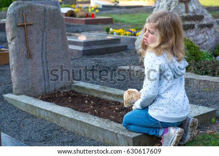 little sad girl in front of grave