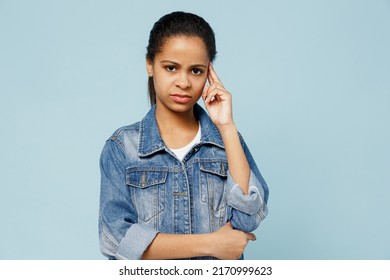 Little Sad Kid Teen Girl Of African American Ethnicity 12-13 Years Old In Denim Jacket Look Camera Prop Up Forehead Head Look Camera Isolated On Pastel Plain Light Blue Background. Childhood Concept