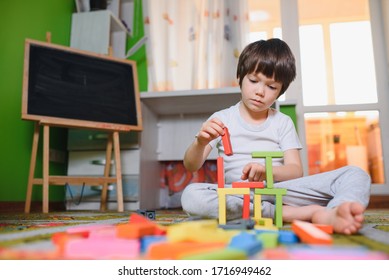 Little Sad Thoughtful Bored Toddler Boy Playing Colorful Building Blocks Alone At Home During Quarantine. Development Game. Loneliness At Self Isolation Period