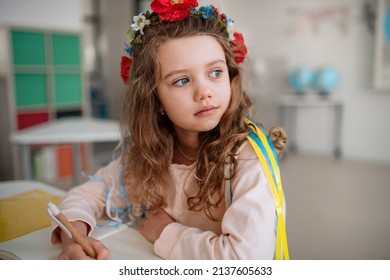 Little sad Ukrainian girl sitting in classroom during class, concept of enrolling Ukrainian kids to schools. - Powered by Shutterstock