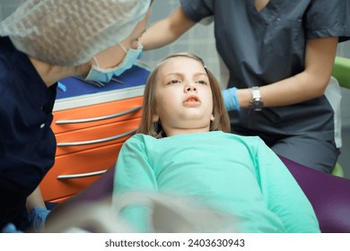 Little scared girl sitting in chair in dentist doctor office. Kid,child afraid of tooth extraction, teeth treatment, examine with open mouth. Dental clinic check-up. Reclined position. Dentist gloves. - Powered by Shutterstock