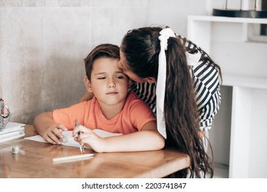 Little School Boy Doing Homework With His Mom Kissing Him On The Head