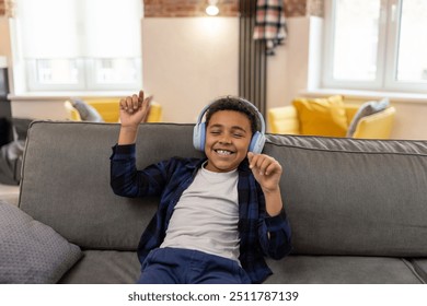 Little school boy wearing headphones listening to music and dancing - Powered by Shutterstock