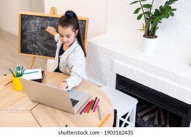 Little school Girl Writing Letters on Blackboard. Toddler girl holding chalk and drawing at home, distant education