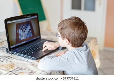 Little School Kid Boy With Glasses Playing Online Chess Board Game On Computer. Child Having Fun With Learning On Pc. Education Concept.