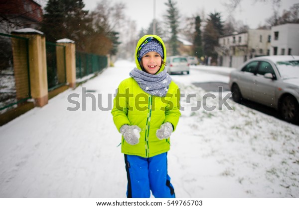 Little schoolboy goes down the street
in winter day. The boy is dressed in a bright ski suit. It is
snowing. The child likes such weather. He cheerfully
smiles.